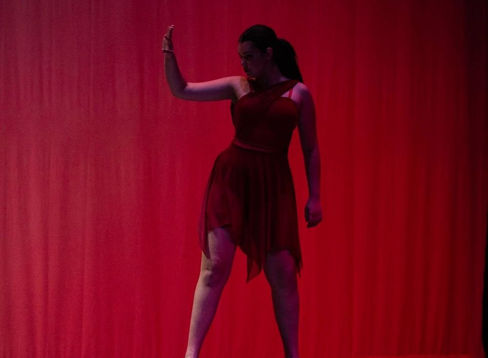 A dancer in red against a red curtain