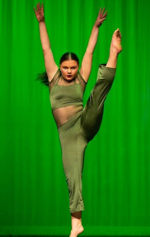 A dancer in green holding a high extension
