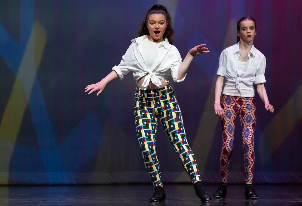 Two tap dancers on stage in printed leggings